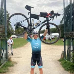 Serge Schnegg portant son vélo au-dessus de sa tête après le défi Paris-Brest-Paris